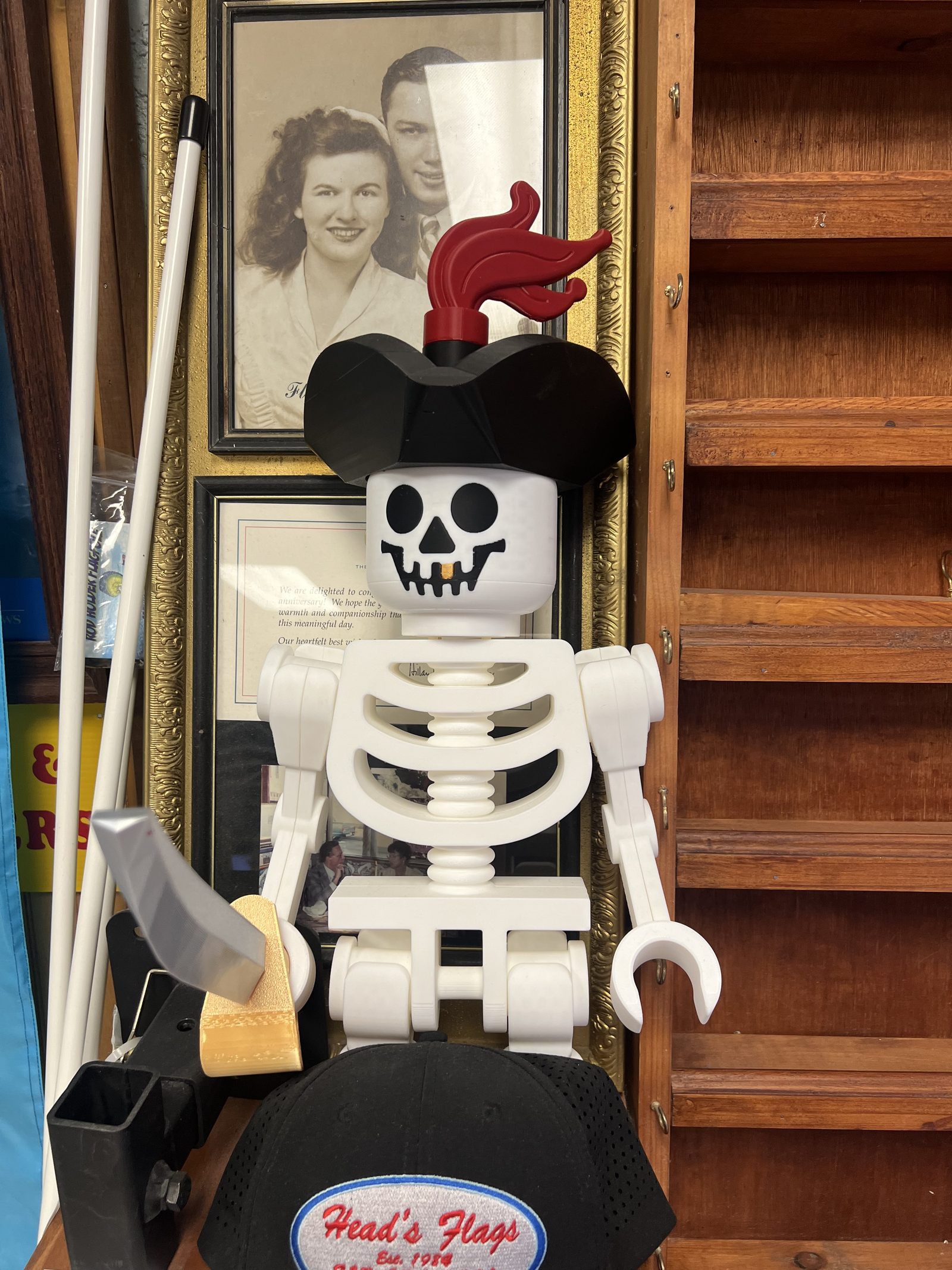 The shop mascot, a pirate skeleton in a Head's Flags cap, beside a family photograph